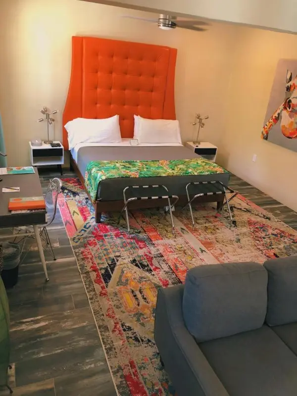 Une chambre colorée avec un grand lit et un coin salon.