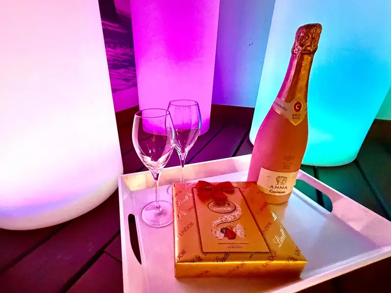 Une bouteille de champagne et des chocolats sont servis sur un plateau.