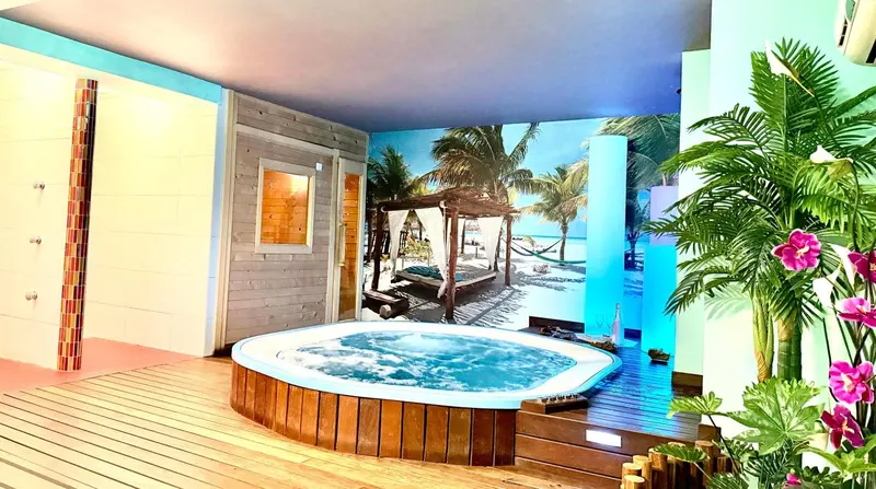 Un jacuzzi rond est intégré dans une pièce décorée sur le thème tropical.