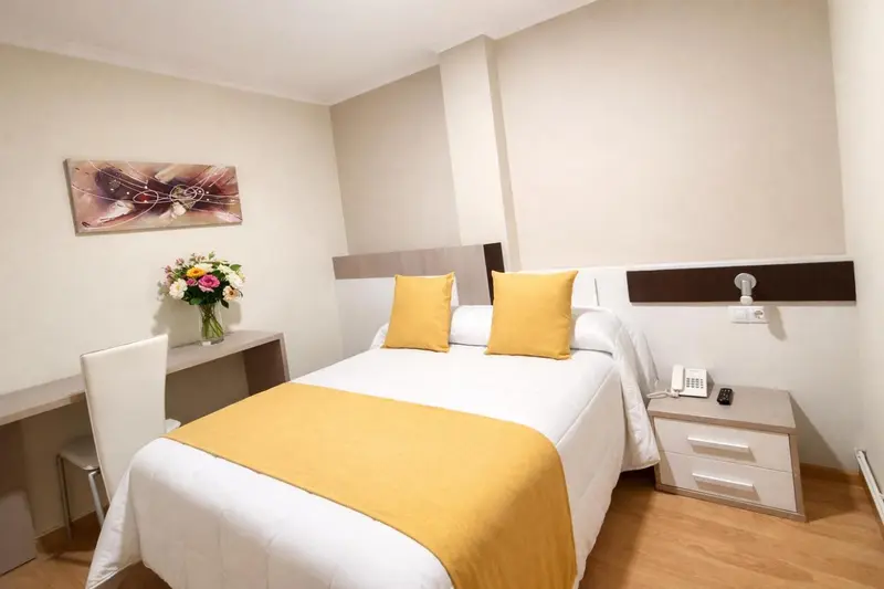 Une chambre lumineuse avec un lit recouvert d'une courtepointe et de coussins.