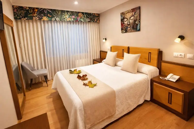 Une chambre lumineuse avec un grand lit décoré de feuilles.