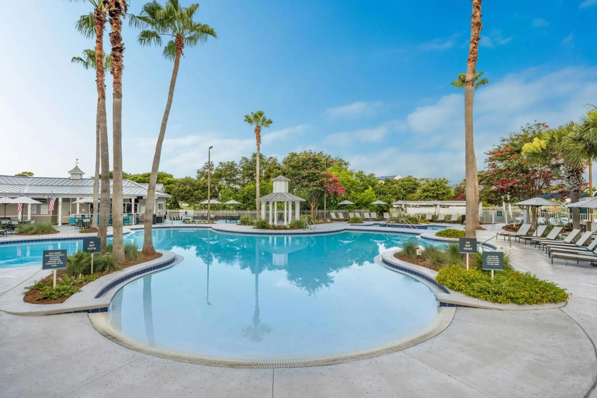 Une piscine rectangulaire avec des palmiers et des transats.
