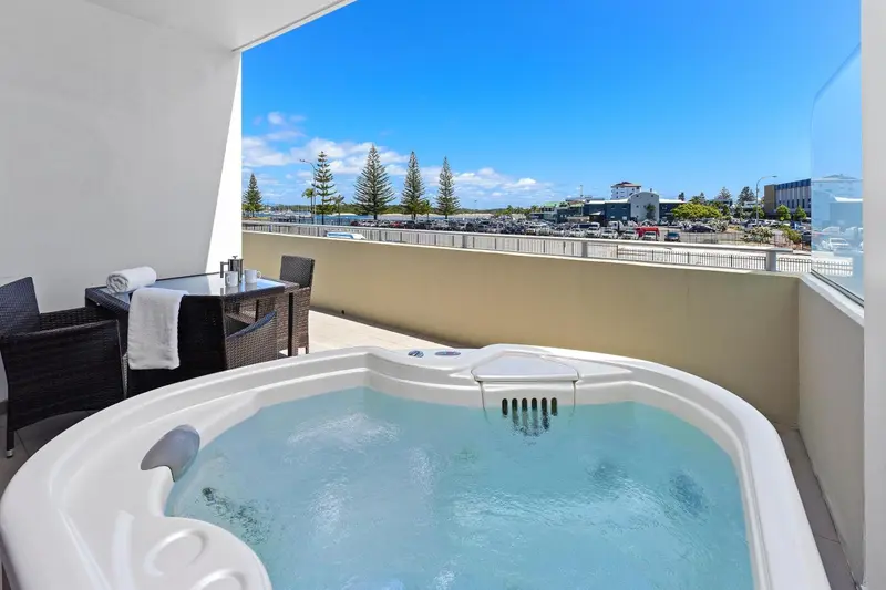 Un jacuzzi sur une terrasse avec vue sur la mer et la ville.