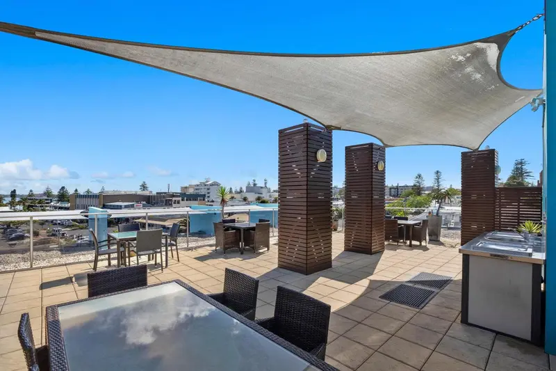 Terrasse ombragée avec mobilier de jardin et vue sur la ville.