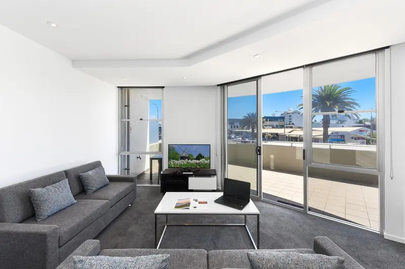 Un salon moderne avec canapé gris et vue sur la mer par de grandes baies vitrées.