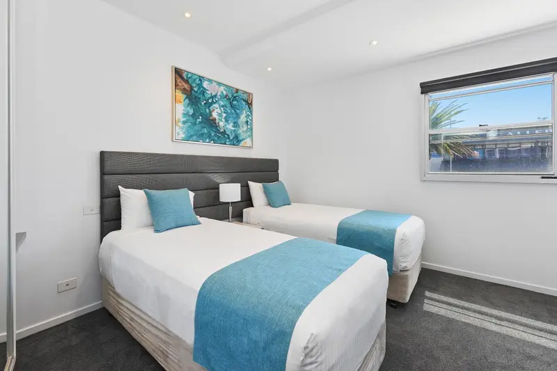 Chambre lumineuse avec deux lits simples et une décoration moderne.