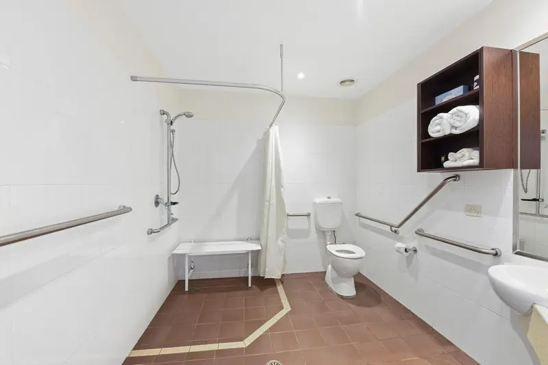 Une salle de bain claire avec douche à l'italienne et toilettes.