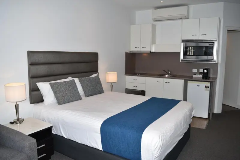 Une chambre avec un lit et une kitchenette.