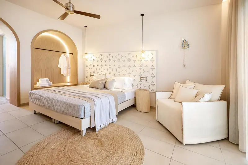 Une chambre lumineuse avec un grand lit et un coin salon.