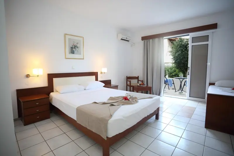 Une chambre lumineuse avec un lit blanc et un accès à une terrasse.