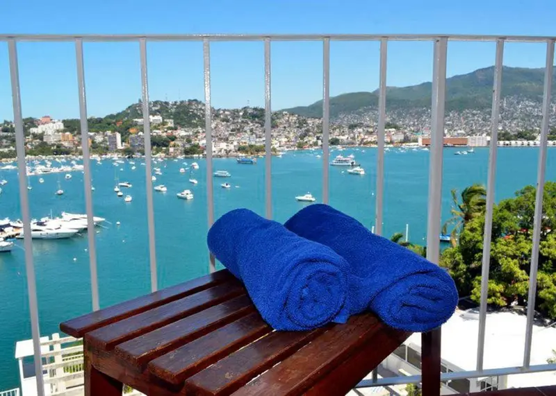 Vue sur une baie ensoleillée depuis un balcon avec des serviettes.