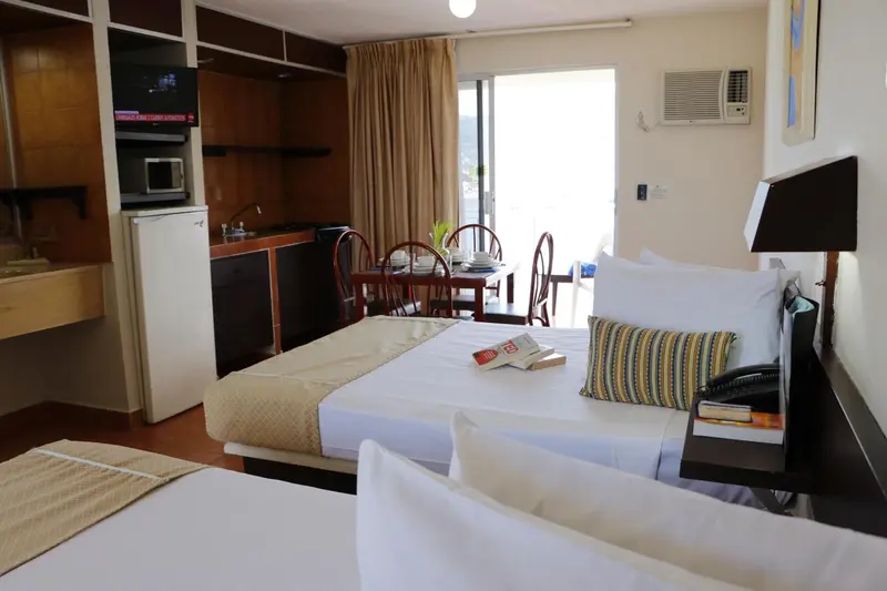 Une chambre lumineuse avec un lit, une kitchenette et une table à manger.