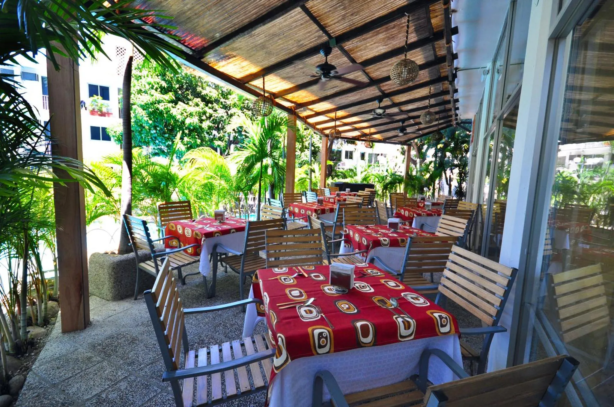 Terrasse ombragée avec tables et chaises disposées pour les repas.