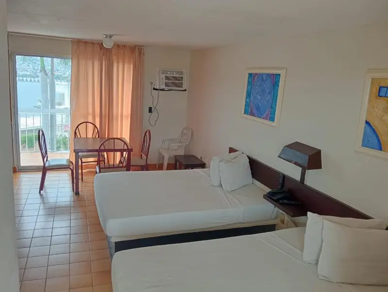 Une chambre lumineuse avec un lit, une table et des chaises près d'une baie vitrée.