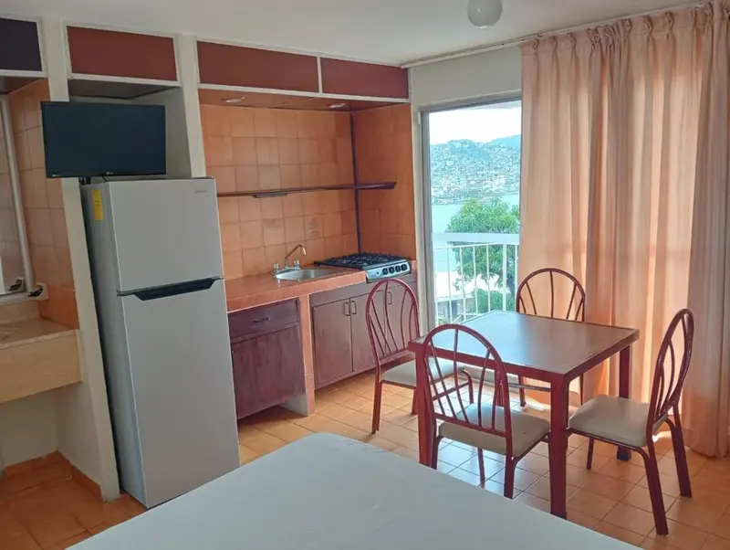 Une kitchenette avec une table et des chaises près d'une fenêtre.