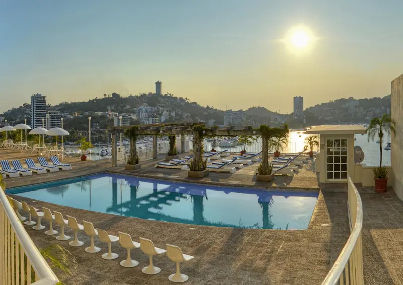 Terrasse avec piscine et vue sur la mer au coucher du soleil.