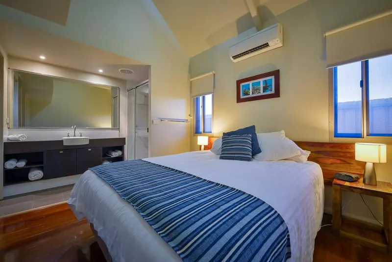 Une chambre lumineuse avec un grand lit et un espace salle de bain attenant.