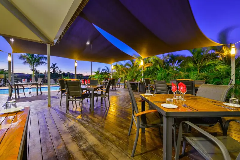 Terrasse ombragée avec tables dressées pour le dîner.