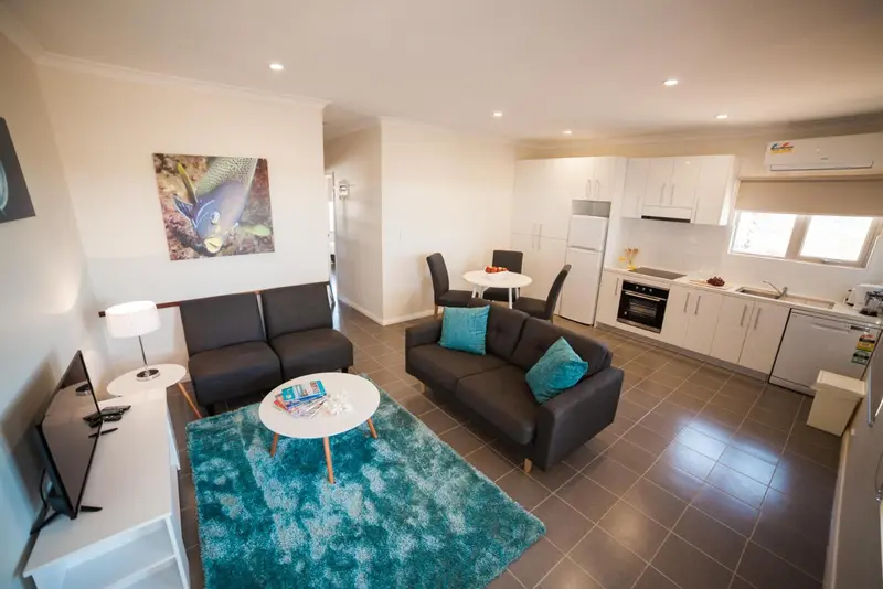 Espace de vie lumineux avec canapé, table et cuisine équipée.