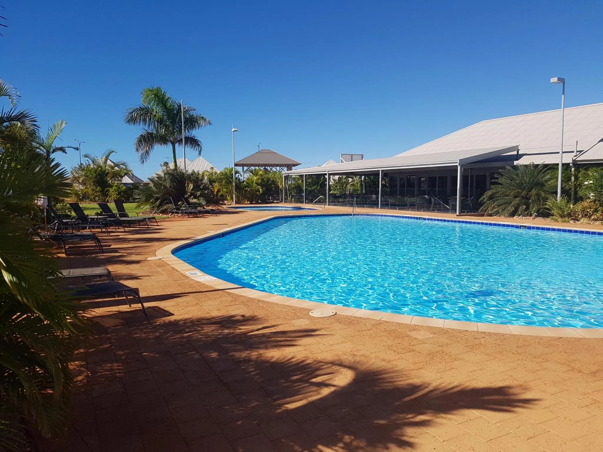 Une piscine rectangulaire bordée d'une terrasse ensoleillée avec des transats.