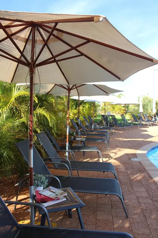 Transats et parasols ombragent une terrasse ensoleillée.