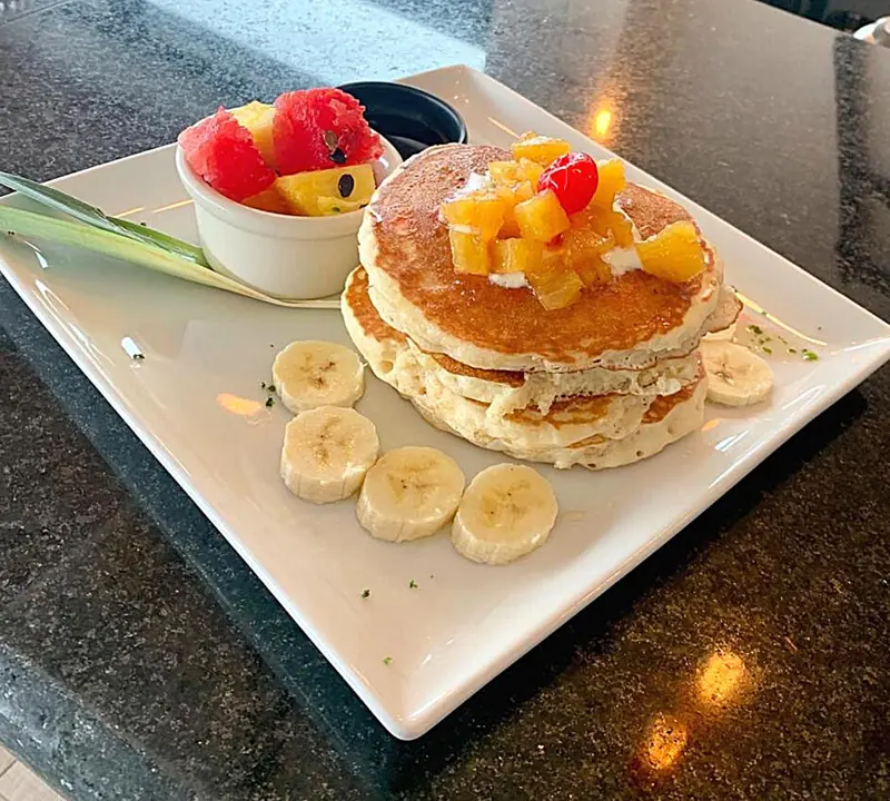 Assiette de pancakes garnis de fruits frais et de crème.