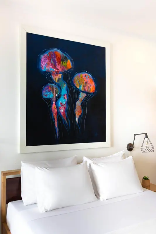 Une décoration murale abstraite représentant des méduses illumine une chambre avec un lit blanc.