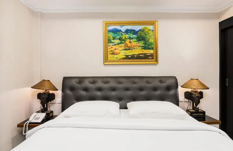 Une chambre avec un grand lit et un tableau décoratif au mur.