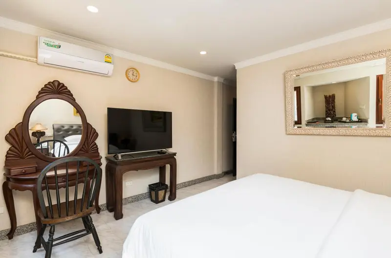 Une chambre lumineuse avec un lit blanc et un meuble de télévision.