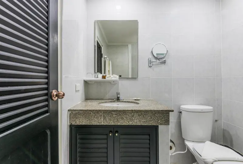 Une salle de bain claire avec lavabo, miroir et toilettes.