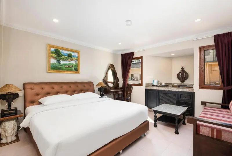 Une chambre lumineuse avec un grand lit et un coin salon.