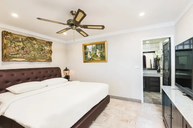 Une chambre avec un grand lit et des tableaux décoratifs.