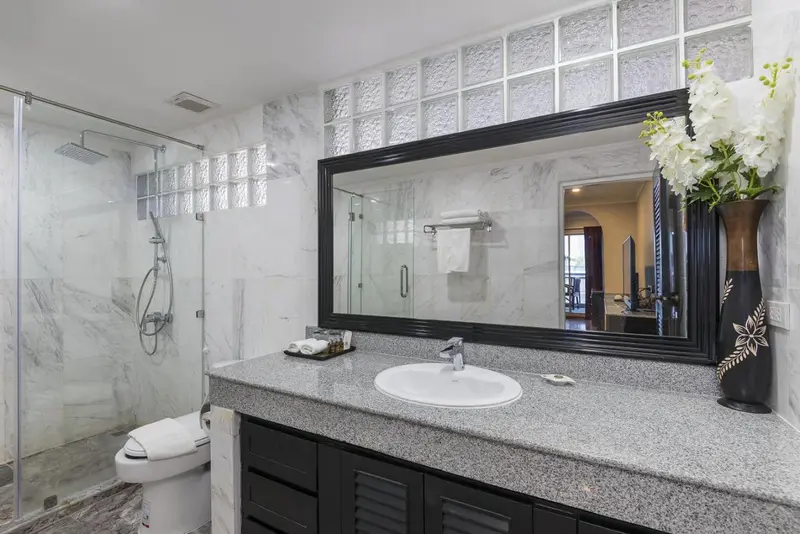 Une salle de bain lumineuse avec douche à l'italienne et grand miroir.