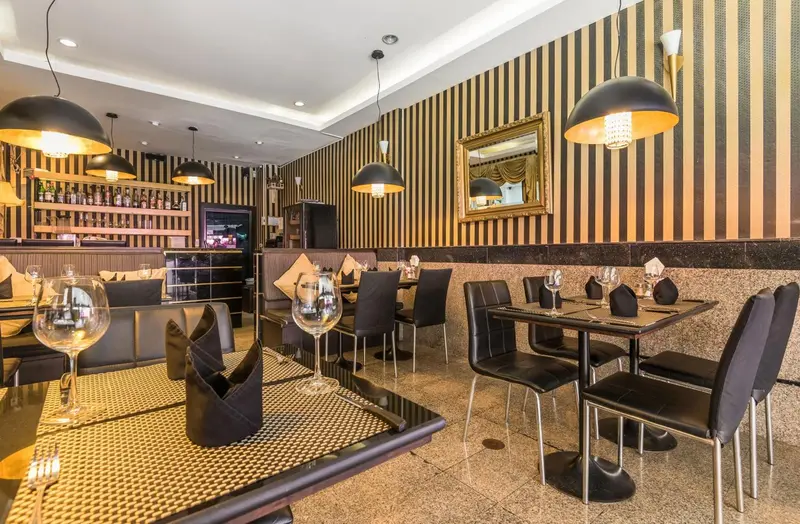 Une salle de restaurant avec des tables dressées et un comptoir de boissons.