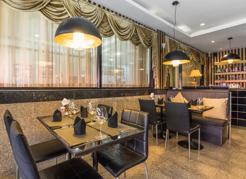 Une salle de restaurant avec des tables dressées et des luminaires suspendus.