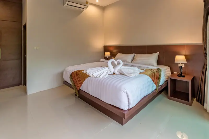 Une chambre lumineuse avec un grand lit décoré de serviettes en forme de cygnes.