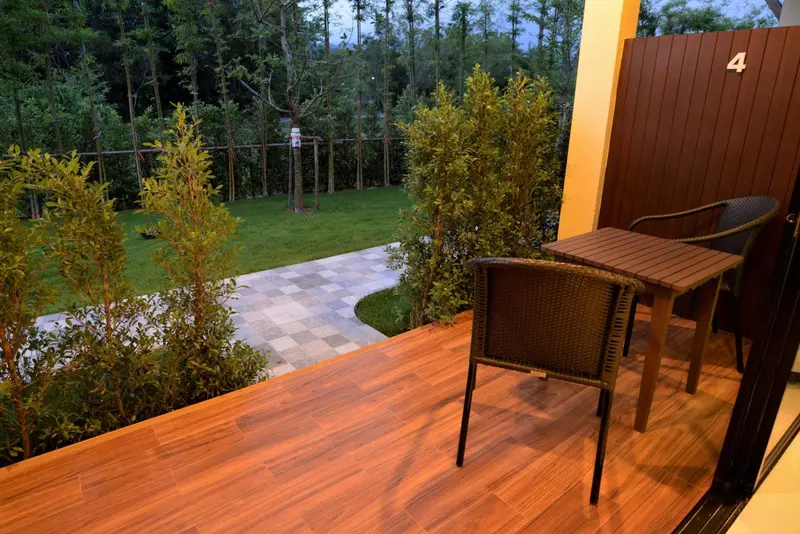 Une terrasse en bois avec une table et des chaises, donnant sur un jardin soigné.