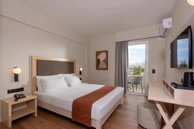 Une chambre lumineuse avec un grand lit et un balcon.