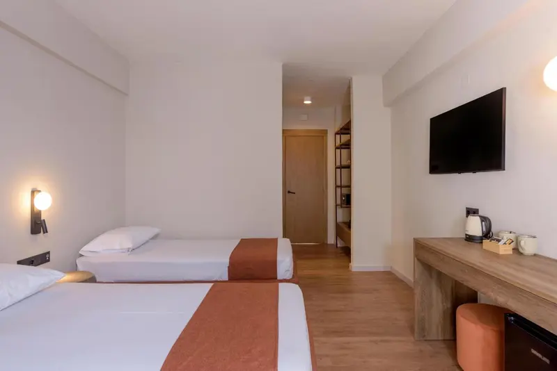 Une chambre lumineuse avec deux lits simples et un bureau.