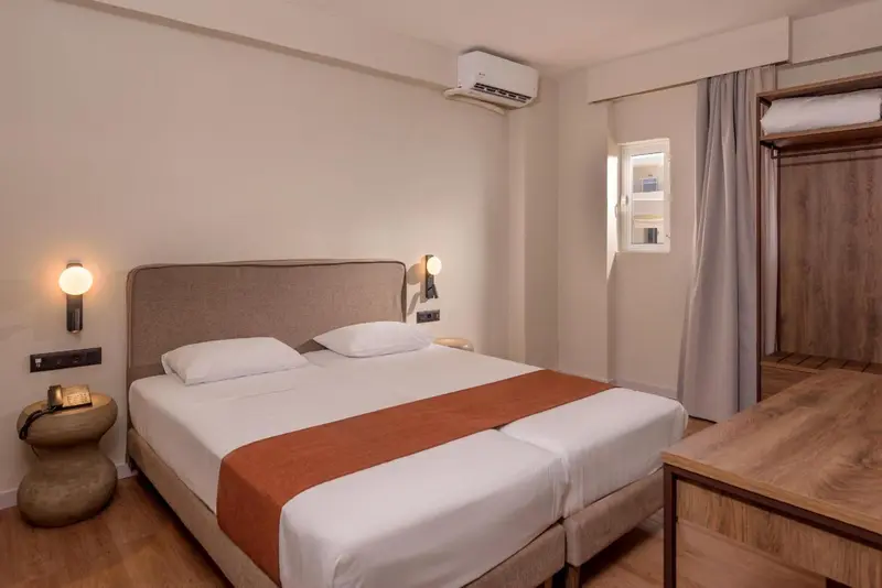 Une chambre avec un grand lit recouvert d'une courtepointe orange et de coussins blancs.