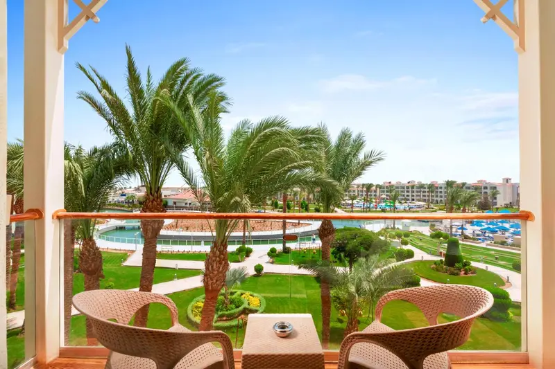 Vue sur une végétation luxuriante et une piscine depuis un balcon aménagé.