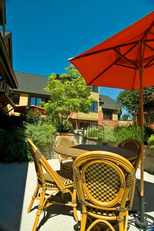 Une table et des chaises en osier sont disposées sur une terrasse ensoleillée.