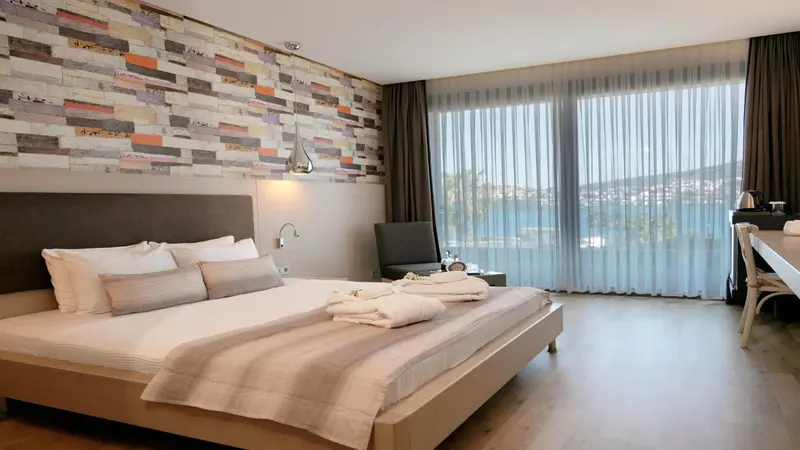 Une chambre lumineuse avec un grand lit et une vue sur la mer.