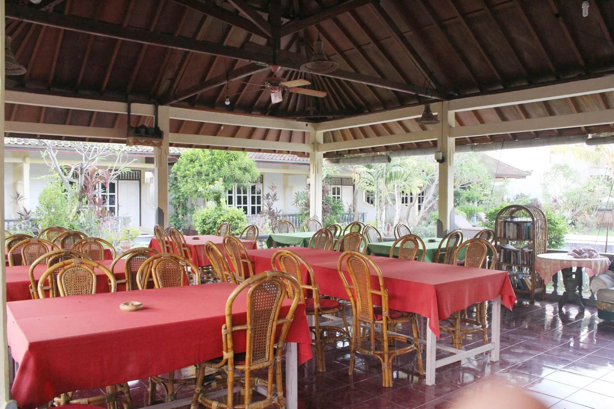 Une salle à manger extérieure avec des tables et des chaises en rotin sous un toit de chaume.