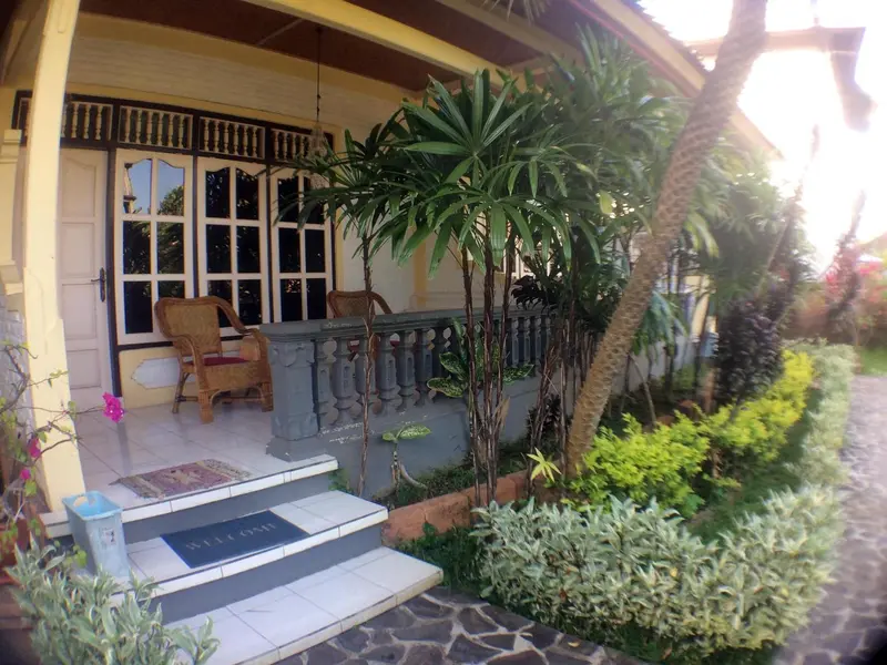Terrasse ombragée avec mobilier en bois et végétation tropicale.