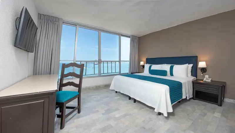 Une chambre lumineuse avec un grand lit et une vue sur la mer.