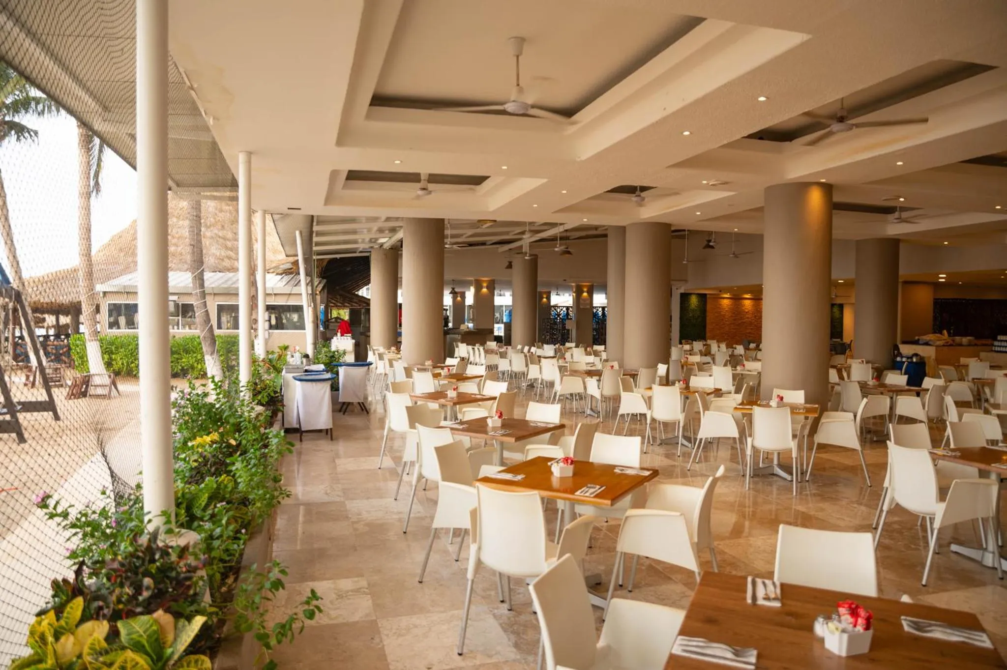Une salle lumineuse avec des tables et des chaises est prête pour le service.