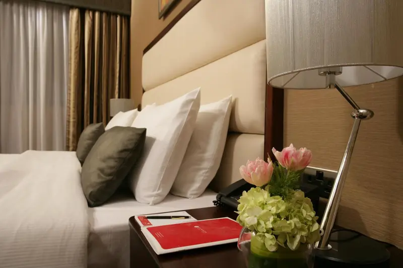 Un lit confortable avec des oreillers et une décoration florale sur une table de chevet.