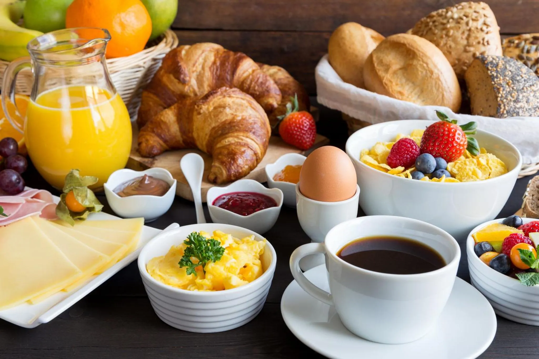 Une table garnie de viennoiseries, de fruits frais, de céréales et de boissons.