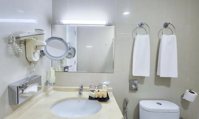 Une salle de bain claire avec un miroir lumineux et des serviettes blanches.